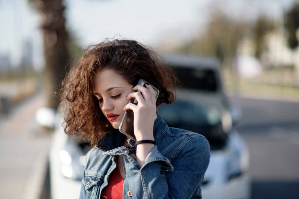 unhappy woman with a broken down car calling roadside assistance