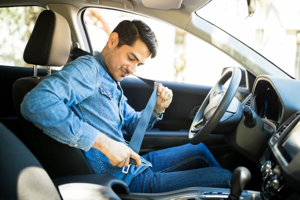 hispanic man fastening seat belt